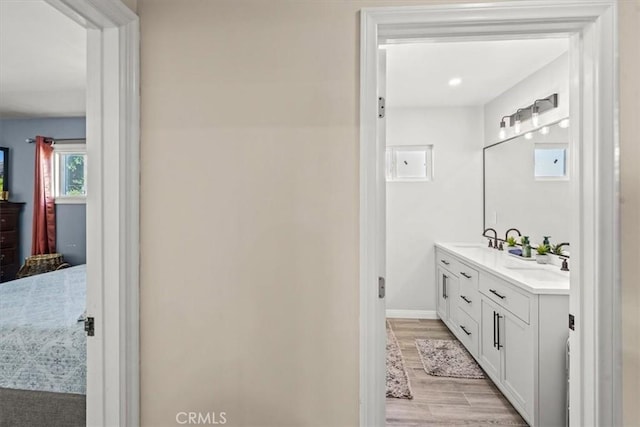 bathroom featuring double vanity, a sink, baseboards, and wood finished floors