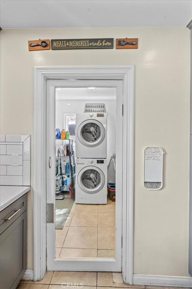 washroom with laundry area, light tile patterned flooring, and stacked washer / drying machine