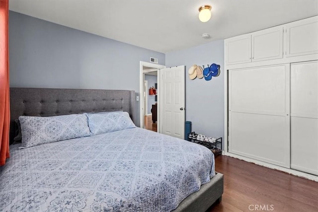 bedroom with a closet, visible vents, and dark wood-style flooring