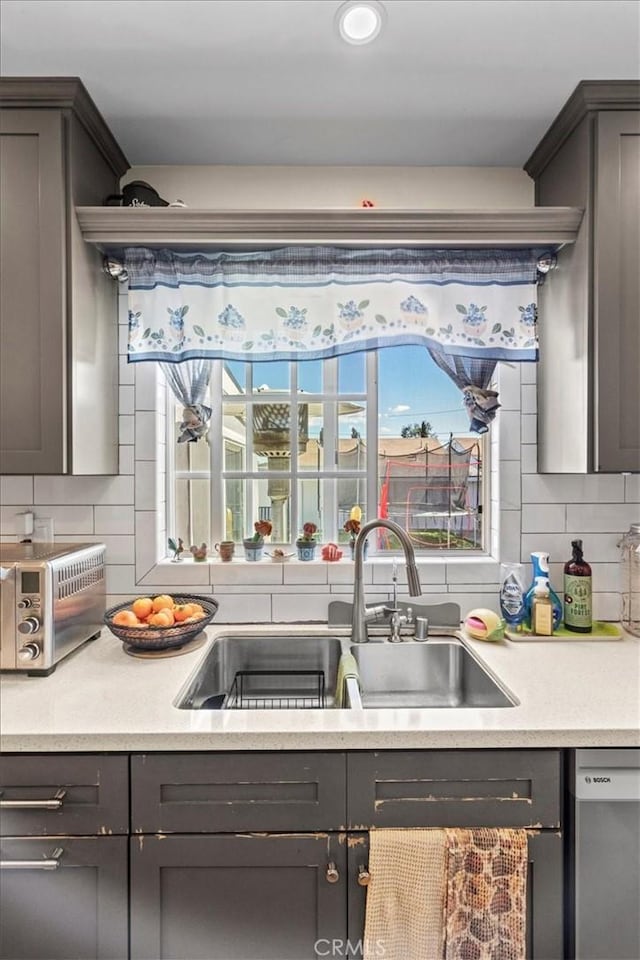 kitchen with stainless steel dishwasher, plenty of natural light, decorative backsplash, and a sink