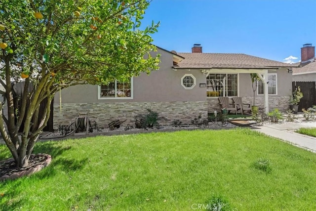 view of front of house featuring stone siding, a chimney, a front lawn, and stucco siding