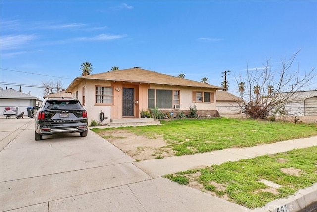 bungalow-style home featuring a front lawn and stucco siding