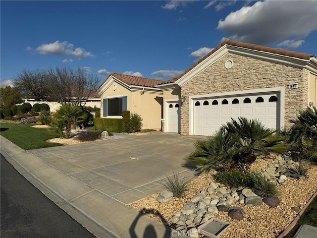 mediterranean / spanish home with concrete driveway, stone siding, a tiled roof, an attached garage, and stucco siding