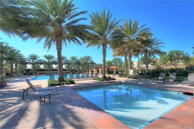 community pool with fence and a patio area