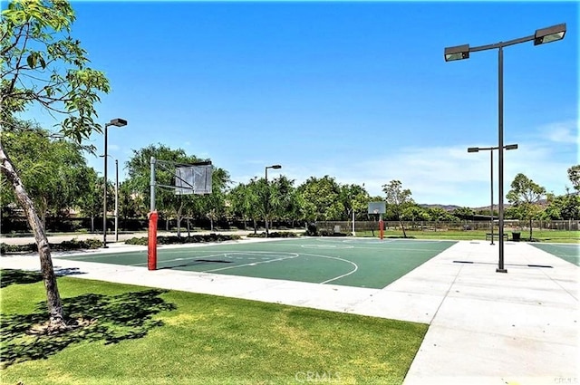 view of basketball court featuring community basketball court, a lawn, and fence
