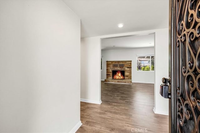 foyer entrance featuring a stone fireplace, recessed lighting, baseboards, and wood finished floors