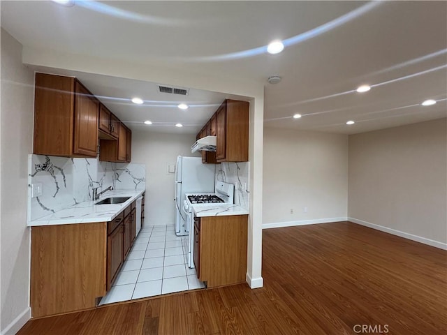 kitchen with gas range gas stove, visible vents, a sink, light wood-type flooring, and under cabinet range hood