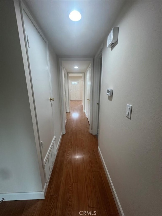 corridor featuring visible vents, baseboards, and wood finished floors