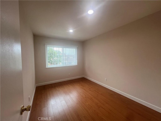 empty room featuring dark wood-style flooring, recessed lighting, and baseboards