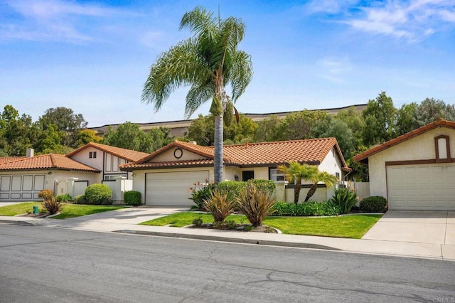 view of front of house with an attached garage, fence, concrete driveway, a tiled roof, and stucco siding