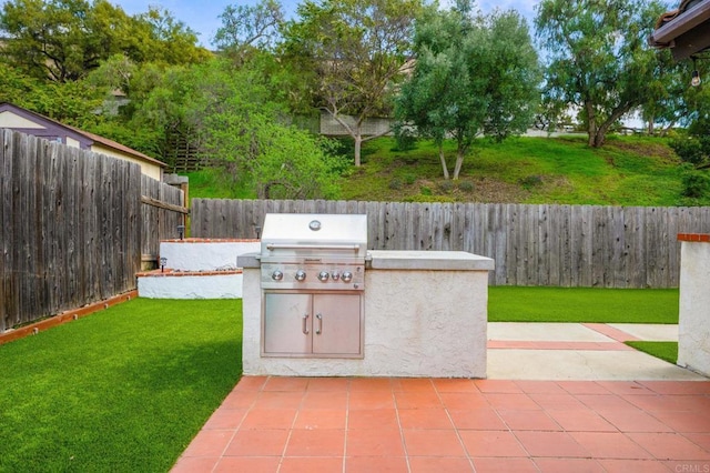 view of patio featuring exterior kitchen, a fenced backyard, and area for grilling