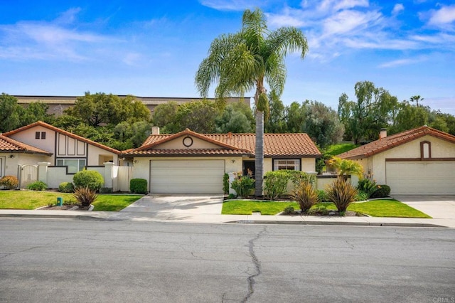 mediterranean / spanish-style home with concrete driveway, a tiled roof, an attached garage, fence, and stucco siding