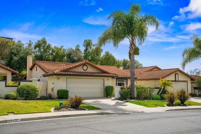 mediterranean / spanish home featuring concrete driveway, a chimney, a tiled roof, an attached garage, and stucco siding