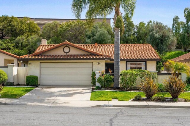 mediterranean / spanish house featuring a garage, concrete driveway, a tile roof, and stucco siding