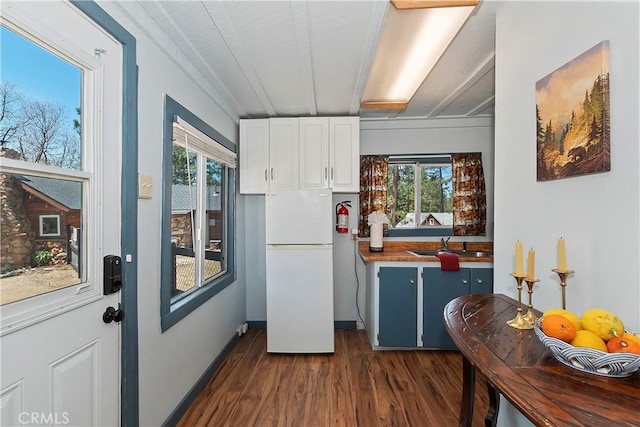 kitchen with dark wood-style floors, white cabinets, a sink, and freestanding refrigerator