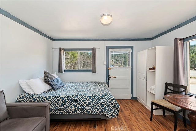 bedroom with ornamental molding and wood finished floors