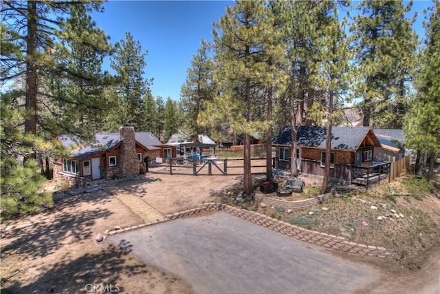 view of front of property with a deck, driveway, and a chimney