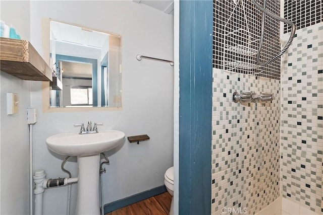 full bath featuring toilet, a sink, wood finished floors, tiled shower, and baseboards