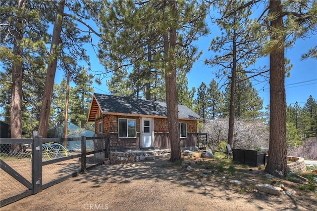 chalet / cabin featuring a gate, fence, and roof with shingles