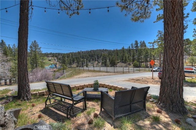 view of community featuring fence and a wooded view