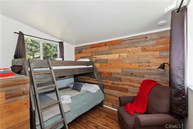 bedroom featuring vaulted ceiling, wood walls, and wood finished floors