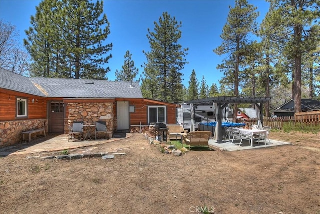 back of property with roof with shingles, a patio, fence, a pergola, and stone siding