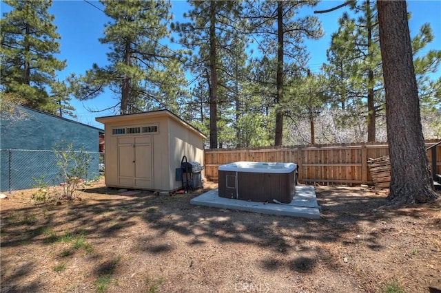 view of yard with an outbuilding, a storage unit, a fenced backyard, and a hot tub