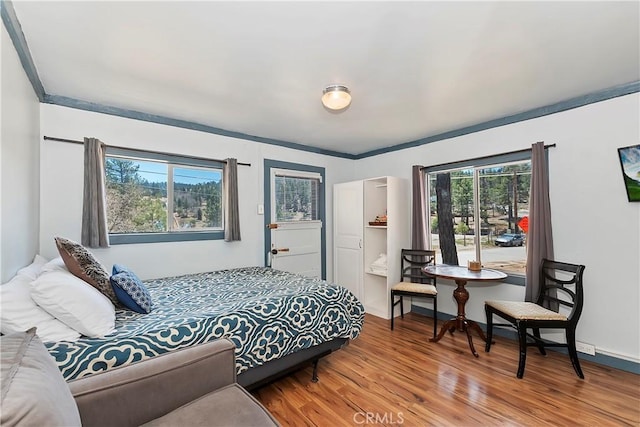 bedroom featuring baseboards, wood finished floors, and crown molding