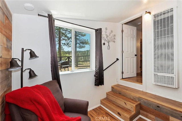 living area with stairs, a heating unit, and wood finished floors