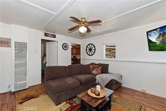 living room with ceiling fan, a heating unit, and wood finished floors