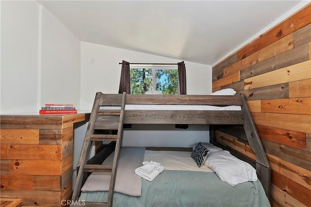 bedroom with vaulted ceiling and wood walls