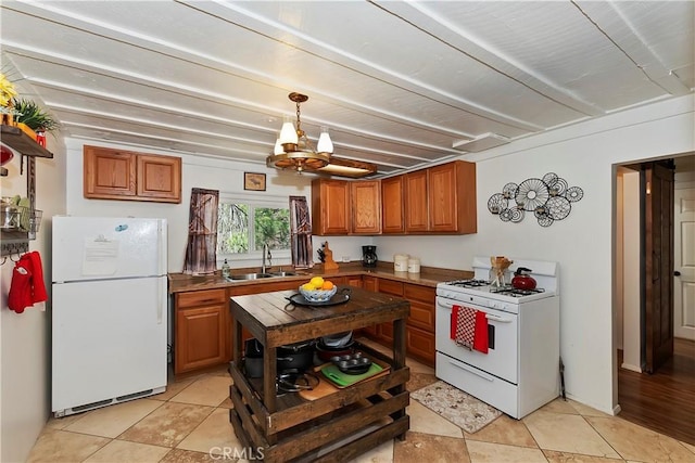 kitchen with brown cabinetry, white appliances, a sink, and beam ceiling