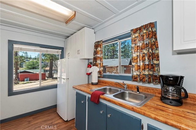 kitchen with a wealth of natural light, freestanding refrigerator, white cabinetry, and a sink