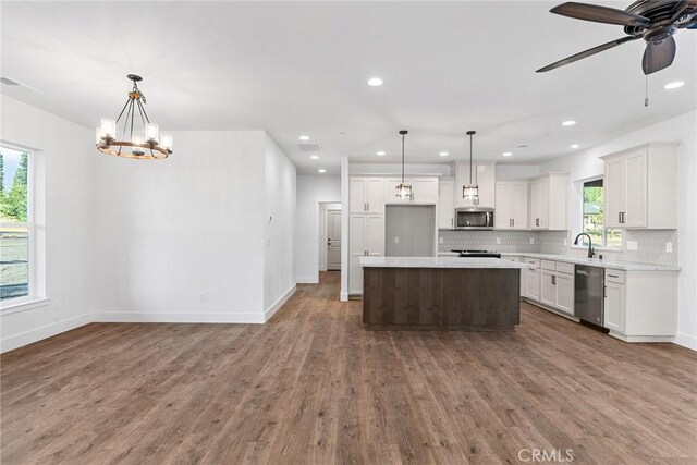 kitchen with tasteful backsplash, appliances with stainless steel finishes, light countertops, and dark wood-style flooring