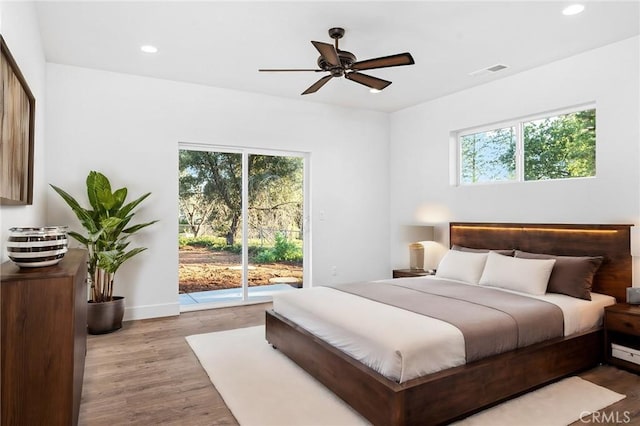 bedroom featuring access to outside, multiple windows, wood finished floors, and recessed lighting