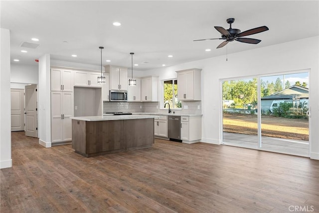 kitchen with appliances with stainless steel finishes, backsplash, dark wood-style flooring, and light countertops