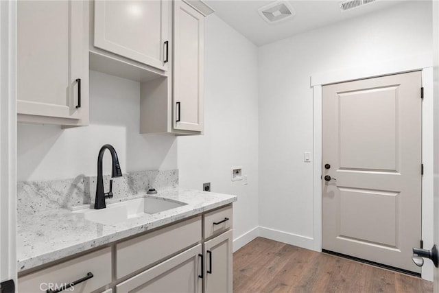 laundry room with washer hookup, cabinet space, light wood-style floors, hookup for an electric dryer, and a sink