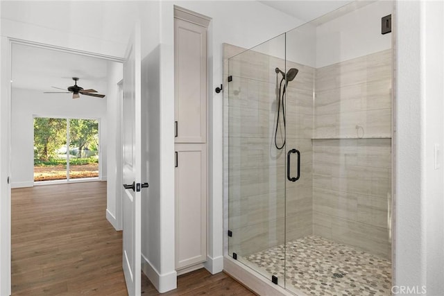 full bathroom featuring baseboards, ceiling fan, wood finished floors, and a shower stall