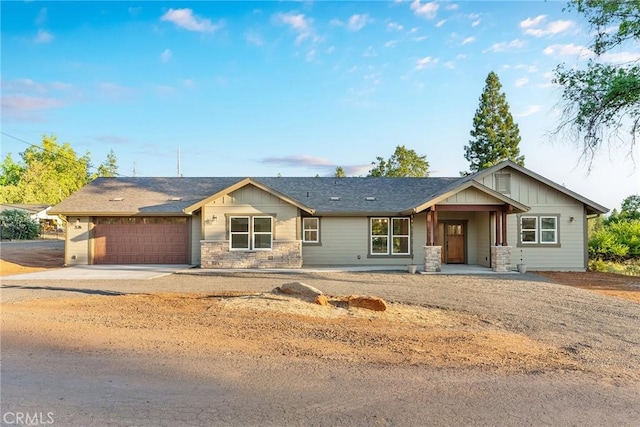 ranch-style home with board and batten siding, stone siding, driveway, and an attached garage