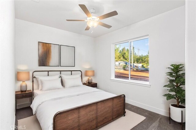 bedroom with baseboards, dark carpet, and ceiling fan