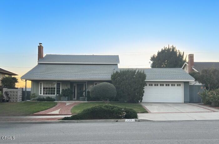 view of front of home featuring a front lawn, fence, concrete driveway, a chimney, and a garage