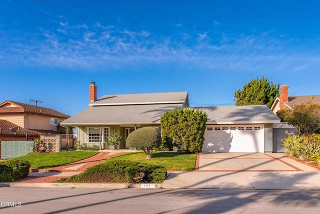 view of front of property featuring a garage, concrete driveway, a front lawn, and fence