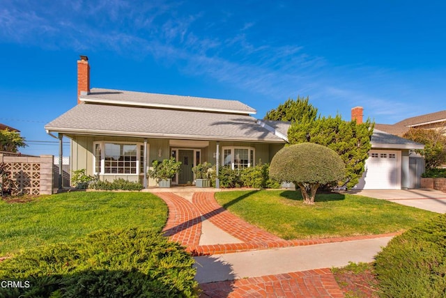 view of front of home with driveway, a shingled roof, an attached garage, a front yard, and a chimney