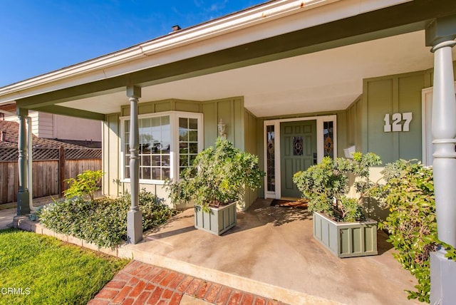 view of exterior entry featuring a porch and fence