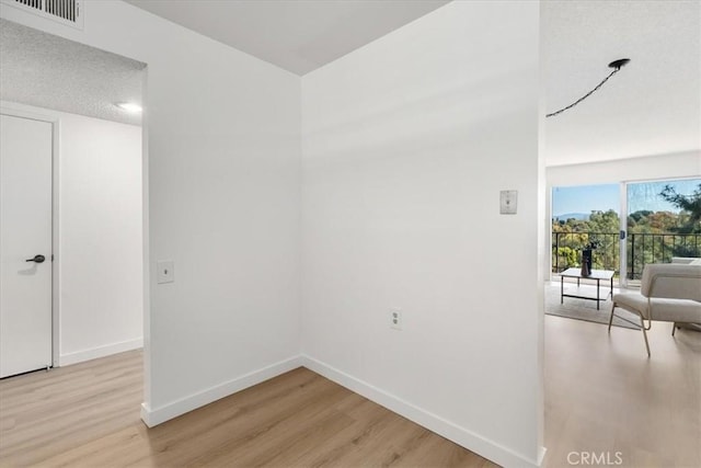 empty room with visible vents, light wood-style flooring, and baseboards