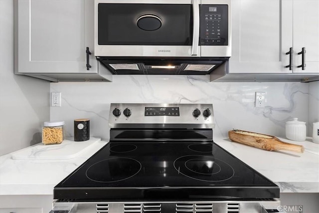 kitchen with decorative backsplash, white cabinetry, and appliances with stainless steel finishes