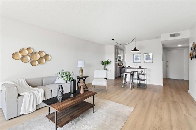 living area with light wood-style floors, visible vents, and a textured ceiling