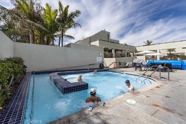 community pool with a patio area and fence