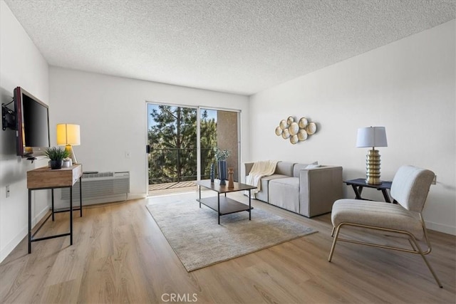 living area with a textured ceiling, baseboards, and wood finished floors