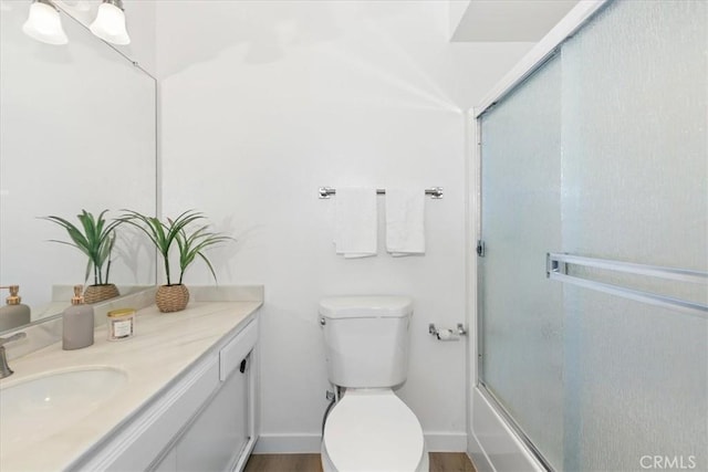 full bathroom featuring vanity, toilet, baseboards, and enclosed tub / shower combo